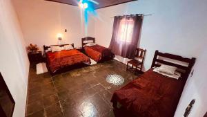 a bedroom with two beds and a window with a blue light at Chale da Pousada Curió in Ibiúna +7 photos