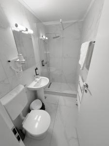 a white bathroom with a toilet and a sink at motel cryss in Ocna Sibiului