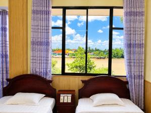 two beds in a room with a window at Hung Vuong Hotel in Ben Tre