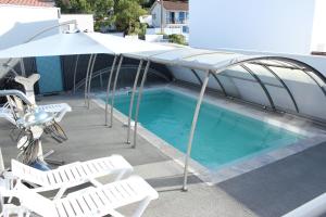 a pool with umbrellas and chairs and a table and chairs at L'Augustémile au bord de l'eau in La Tranche-sur-Mer