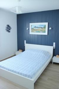 a white bed in a bedroom with a blue wall at L'Augustémile au bord de l'eau in La Tranche-sur-Mer +24 photos