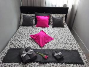 a bed with pink and black pillows and flowers on it at Apartament Junior in Warsaw