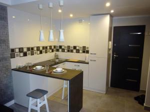 a kitchen with a sink and a counter with a stool at Apartament Junior in Warsaw