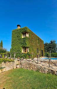 a building covered in ivy next to a stone wall at Sa Sort Llarga in Moscari