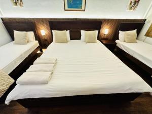 a bedroom with two beds with white sheets and pillows at Subhas Tourist Hotel in Jaffna
