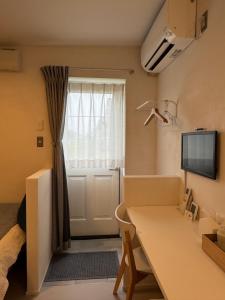 a room with a table and a window with a television at Cafe & Stay Flyway in Ogata