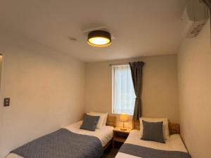 two beds in a room with a window at Cafe & Stay Flyway in Ogata