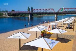 a group of umbrellas on a beach next to a river at Casinha Robusto in Salvaterra de Magos +7 photos