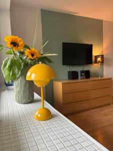 a living room with a vase of sunflowers and a yellow mushroom stool at Hotel Am Mühlenteich in Lübeck