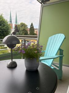 a table with a lamp and a flower pot on a table with a chair at Hotel Am Mühlenteich in Lübeck