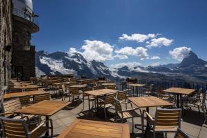 a row of tables and chairs with mountains in the background at 3100 Kulmhotel Gornergrat in Zermatt