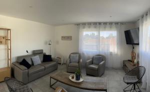 a living room with a couch and chairs and a tv at L'Augustémile au bord de l'eau in La Tranche-sur-Mer