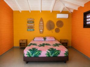 a bedroom with a bed in a room with orange walls at La Baie des Villas in Deshaies