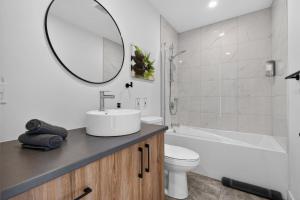 a bathroom with a sink and a toilet and a mirror at Apex Nuage - Spa Game Room & Panoramic Views in Saint Come