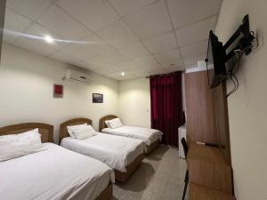 a room with two beds and a flat screen tv at Hotel St Jean in Zahlé