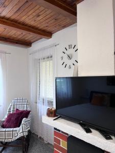 a living room with a tv and a clock on the wall at Ravne Konak in Visoko