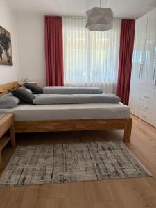 three beds in a bedroom with red curtains at Wohnung im Grünen in Sankt Andrä