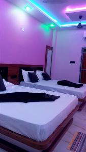 two beds in a hotel room with purple lights at Shri Goara palece in Godarpura