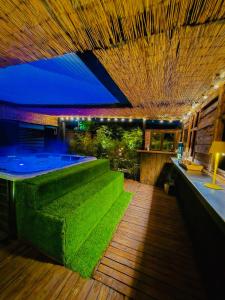 a room with a swimming pool with green grass at Bambuus Garden & Spa in Drăgăşani