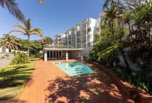 a house with a swimming pool in front of a building at Chakas Cove in Ballito