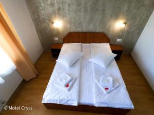 a bedroom with a bed with white sheets and pillows at motel cryss in Ocna Sibiului