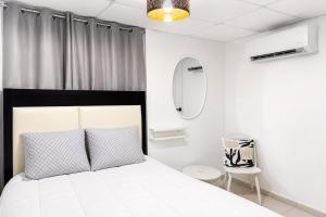 a white bedroom with a bed and a chair at OJAS Local Nest in San Juan