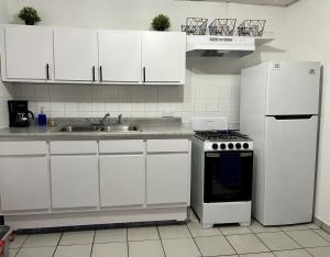 a kitchen with white cabinets and a stove and refrigerator at OJAS Local Nest in San Juan