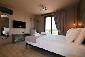 a bedroom with a large white bed and a television at Liostasi Villas by Olga in Leptokarya