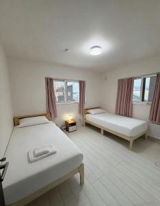 two beds in a room with two windows at 雪宿snow iin in Kutchan