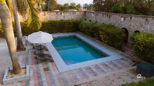 a swimming pool with an umbrella next to a building at Skyblue GuestHouse in Lubumbashi