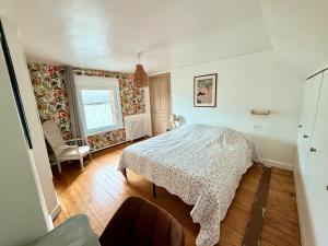 a bedroom with a bed and a chair and a window at Gite Maison Saint-Martin in La Groise