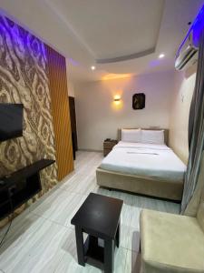 a bedroom with a bed and a tv and a couch at S&B Hotel in Agege