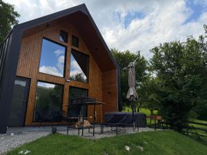 a small wooden house with a grill and an umbrella at Kolibe Doftana in Trăisteni