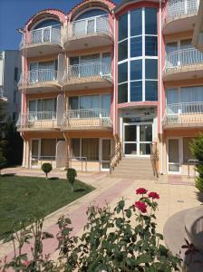 a large building with red flowers in front of it at Sunny House in Kranevo