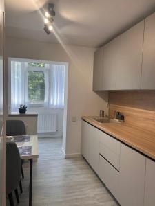 a kitchen with white cabinets and a table and a window at Mangalia Cozy Suite in Mangalia