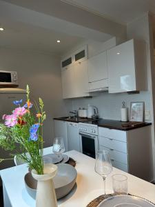 a kitchen with white cabinets and a table with a vase of flowers at KODA Walk Everywhere in Rovaniemi +2 photos