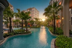 a resort pool with palm trees and buildings at Luxury 2 bedroom pool access apartment in Bang Tao Beach