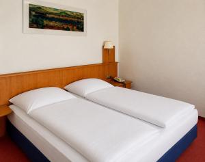 two white beds in a room with a picture on the wall at Hotel Kull von Schmidsfelden in Bad Herrenalb +3 photos