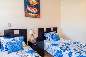 a bedroom with two beds with blue and white pillows at Casa Villa Ensueño in Jacó +23 photos