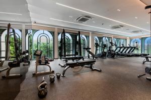 a gym with treadmills and ellipticals in a building with windows at Luxury 2 bedroom pool access apartment in Bang Tao Beach