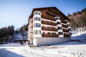 a building in the snow with a bench in front of it at Apartmán Chopok Juh Romantika 14 in Tale