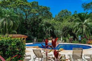 a resort with a pool and chairs and trees at Casa Villa Ensueño in Jacó
