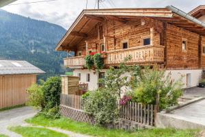 a wooden house with a balcony with flowers at Neuhaus Alm in Gerlosberg