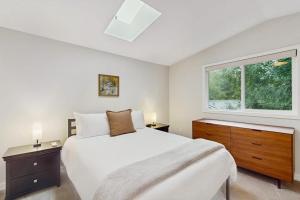 a white bedroom with a large bed and a window at Sanctuary on Park Ave in Hawley