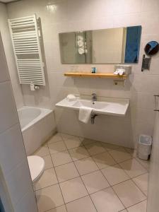 a bathroom with a sink and a tub and a toilet at Hotel het Uilenbos in De Koog