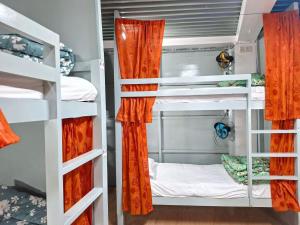 a bedroom with bunk beds with orange curtains at International Dormitory Mohsin Plaza in Sreemangal