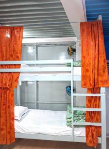 a room with two bunk beds with orange curtains at International Dormitory Mohsin Plaza in Sreemangal