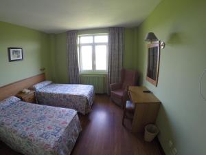 a hotel room with two beds and a chair at Dunas de Oyambre in Comillas