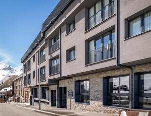 an apartment building on a street with mountains in the background at Estival Caribou Apartments in Pas de la Casa