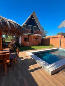 a backyard with a pool and a table and a house at Cabaña Premium Yvyja de La Mala Junta in Atyrá